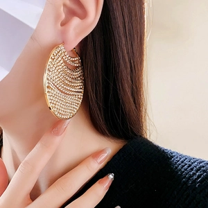Gros plan de créoles en chaîne dorée serties de zircons sur un mannequin femme