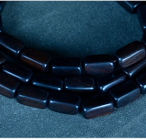 Macro shot of polished rectangular dark ebony wood beads with natural grain detail