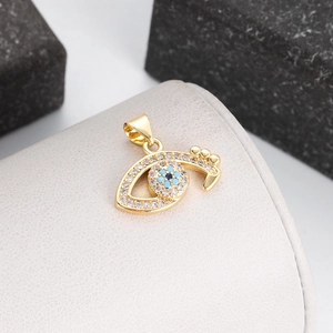 Macro view of gold-plated evil eye pendant with blue zircon stones on a beige display