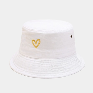 Detailed view of yellow heart embroidery and metal eyelet on white cotton bucket hat