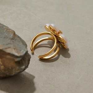 Close-up of golden flower ring with white pearls on natural stone background