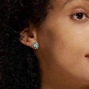 Close-up of moss agate stud earring in silver branch design on model's ear