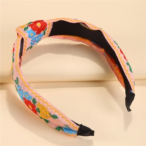 Close-up of pink fabric headband featuring vibrant floral embroidery and knotted design