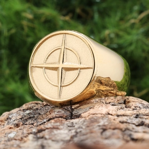 Gold stainless steel compass signet ring for men on a rustic wood background