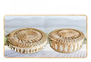 Detail of hand-woven round straw cushion with decorative beige tassels for home decor