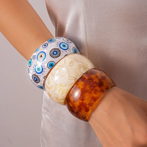 Three acrylic resin bangles in evil eye, cream marble, and amber tortoise patterns