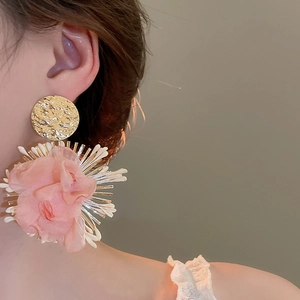 Detailed view of oversized pink chiffon flower earrings with textured gold metal discs