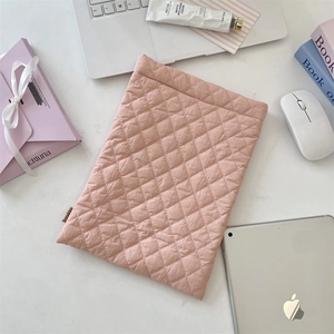 Flat lay of soft pink quilted laptop sleeve with diamond patterns on marble table