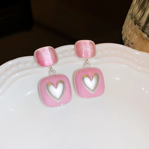 Detailed macro view of heart-shaped pink drop oil floral earrings with cat eye stone inlay
