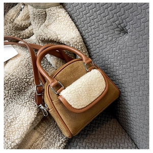 Detail of a brown suede handbag with white faux fur trim and silver hardware accents