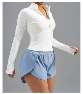 Vue détaillée de la veste de yoga blanche zippée avec passe-pouces et tissu extensible