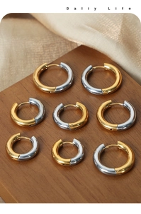 Collection of eight pairs of gold and silver tone titanium steel hoop earrings on wood