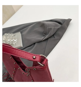 Detail view of burgundy suede tote featuring metallic studs and bohemian fringe accents