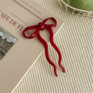 Close-up of a red bow hair pin placed on a vintage book for a balletcore aesthetic