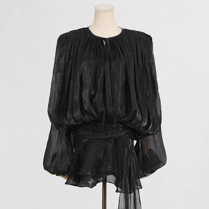 Detail of black satin pleated top featuring puff sleeves and tie collar on a mannequin