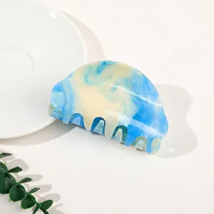 Detailed close-up of blue and white marble pattern acrylic claw clip on a white plate