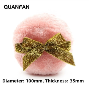 Detail shot of large pink plush powder puff with gold glitter bow showing 100mm diameter