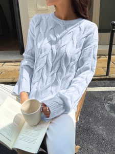 Detailed cable knit pattern on light blue sweater in a cozy outdoor setting