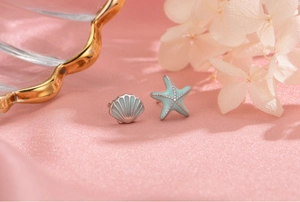 Detail of S925 silver starfish and shell stud earrings with light blue enamel finish