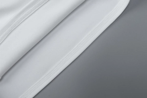 Detailed macro view showing the high-quality double-stitch hem of the white cropped top