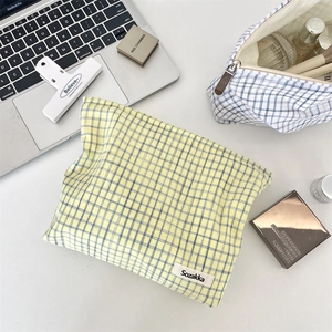 Detailed close-up of blue plaid fabric pouches on a desk with makeup accessories