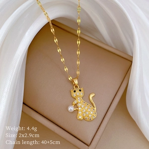 Detailed view of a gold cat pendant with clear gems and a pearl on a white silk base