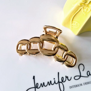 Detail of a hollow chain-style golden metal hair claw clip for elegant hairstyles