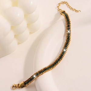 Detail of gold woven chain bracelet with emerald green zircon stones and lobster clasp