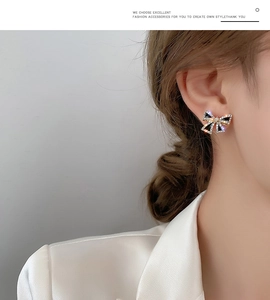 Close-up of s925 gold bow earrings with black finish and white crystals worn by a model