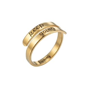 Macro detail of gold-plated stainless steel band with keep going engraved lettering