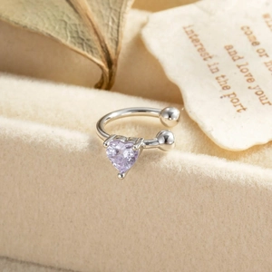 Exquisite silver ear cuff with purple heart zircon gemstone on soft beige velvet surface