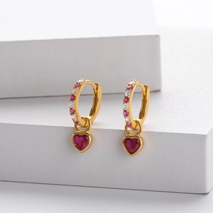 Detail shot of heart-shaped gold earrings with red gems and pink cubic zirconia