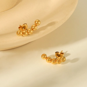 Macro shot of curved five-ball golden titanium steel stud earrings with glossy finish