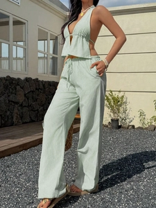 Chic mint green striped halter top and wide-leg trousers set worn by model in courtyard