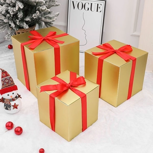 Three-piece gold Christmas gift box set with red silk bows on white faux fur carpet