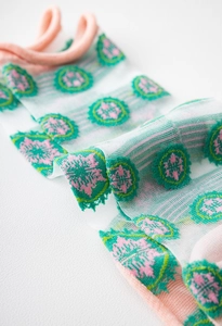 Detailed texture of sheer mesh socks featuring pink cuffs and green floral patterns