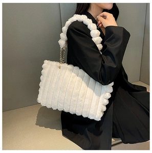 Detail of white plush tote bag with striped texture and unique fluffy pom-pom handle