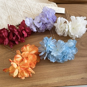 Detail of multi-color fabric flower hairpins in red, white and blue on wooden surface