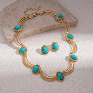 Détail macro du collier géométrique doré vintage et des boucles d'oreilles turquoise
