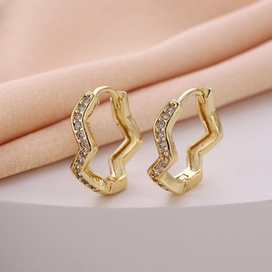 Detailed close-up of golden wavy geometric hoop earrings with sparkling cubic zirconia