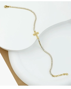 Detail of gold cross bracelet with sparkling cubic zirconia on a minimalist stand