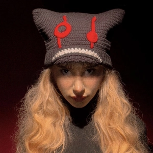 Detailed knit texture of handmade grey cat ear beanie with red devil eye embroidery