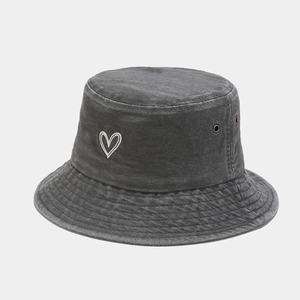 Detail of grey washed cotton bucket hat showing heart embroidery and metal eyelets