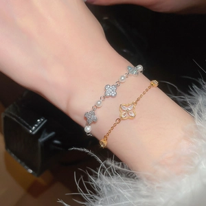 Close-up of elegant clover pearl bracelets in gold and silver on a model's wrist