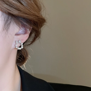 Close-up of elegant silver bow earrings with micro-pave crystals and a white pearl on ear