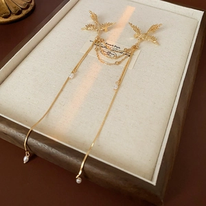 Close-up of golden phoenix bird brooch with pearl tassels on a jewelry display tray