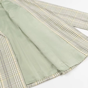 Detailed close-up of light green inner lining and plaid patterned fabric on blazer