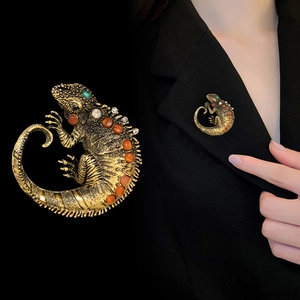 Detailed view of a vintage gold lizard brooch with orange and green rhinestones