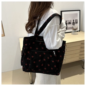 Detailed texture of black corduroy tote bag featuring red strawberry print with pockets