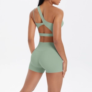 Detail of light green one-shoulder yoga sports bra and high waist seamless fitness shorts
